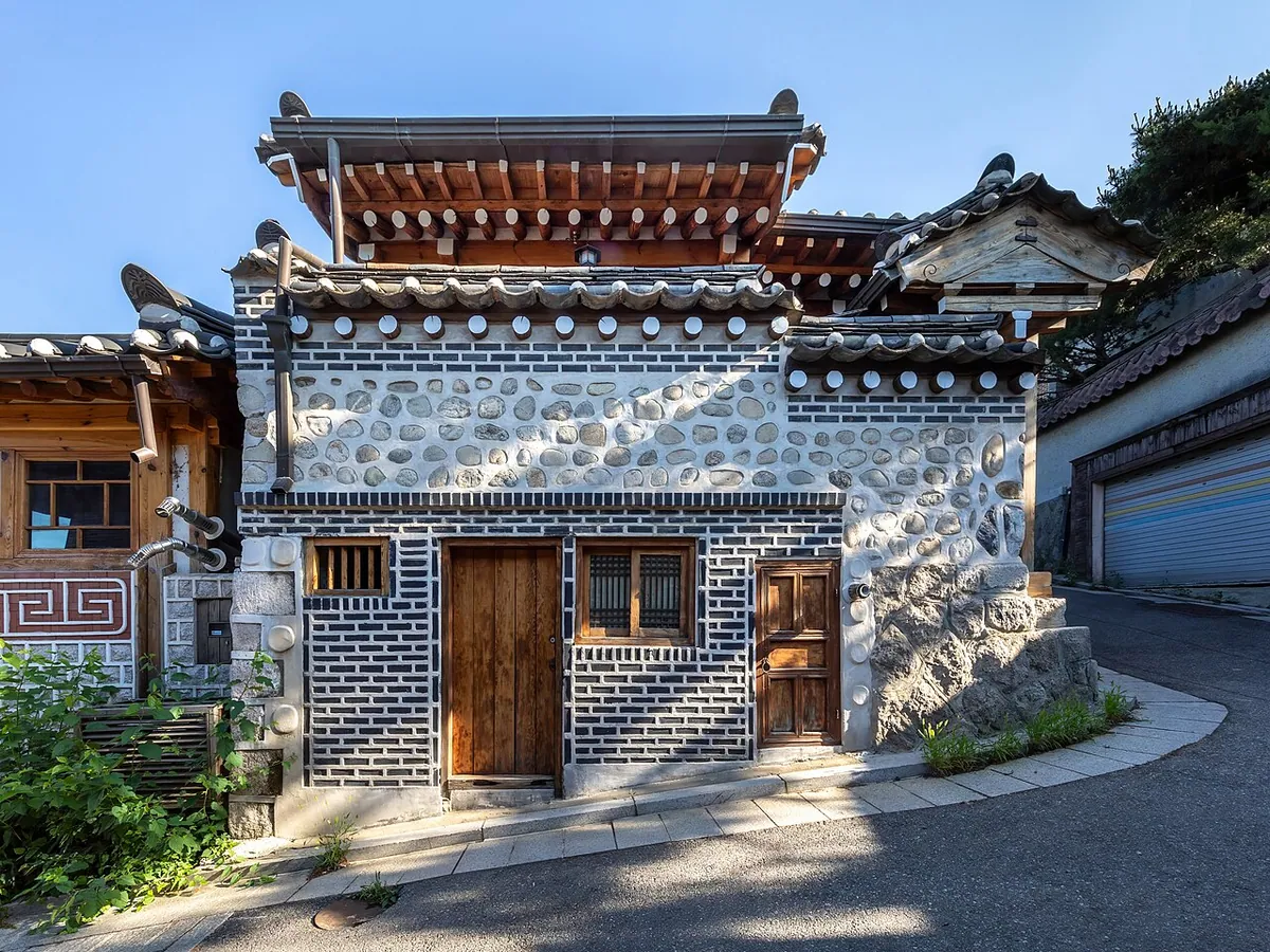 Traditional hanok house with wooden doors along a steeply sloping street in Bukchon Hanok Village Seoul